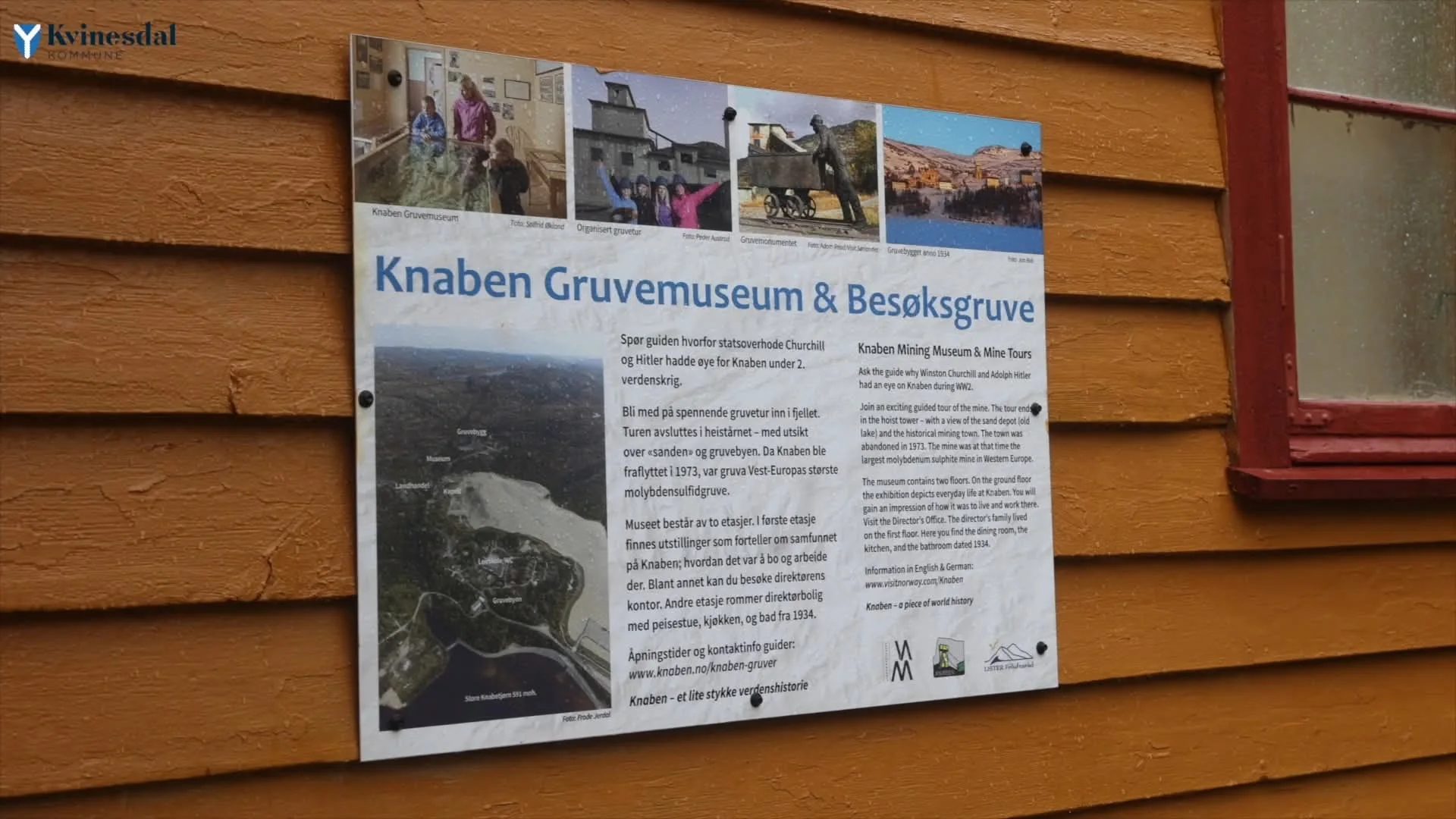 Information sign for Knaben Gruvemuseum og Besøksgruve on an ochre wooden wall, with pictures and an aerial photo of the mining area.