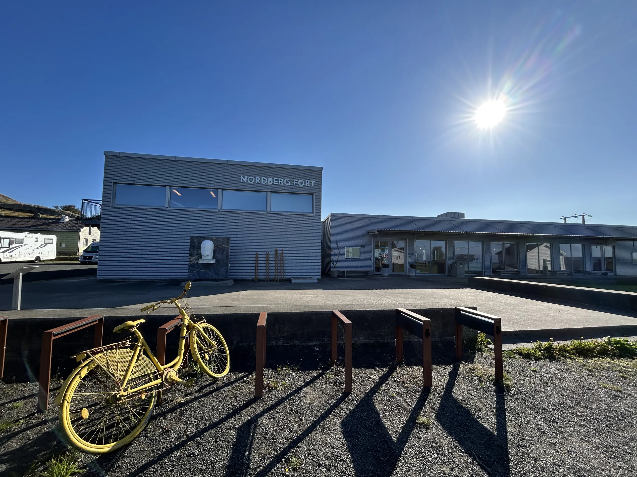 Formidlingsbygget på Nordberg fort i sol, med en gul sykkel foran