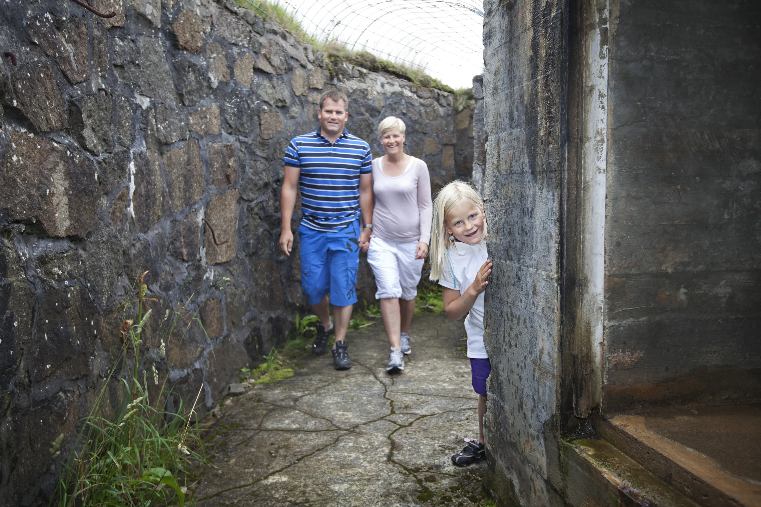 A family walking through a trench between stone walls at Nordberg fort
