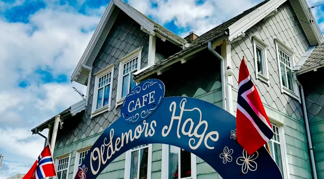 Skiltet til Oldemors hage med det gamle huset i bakgrunnen