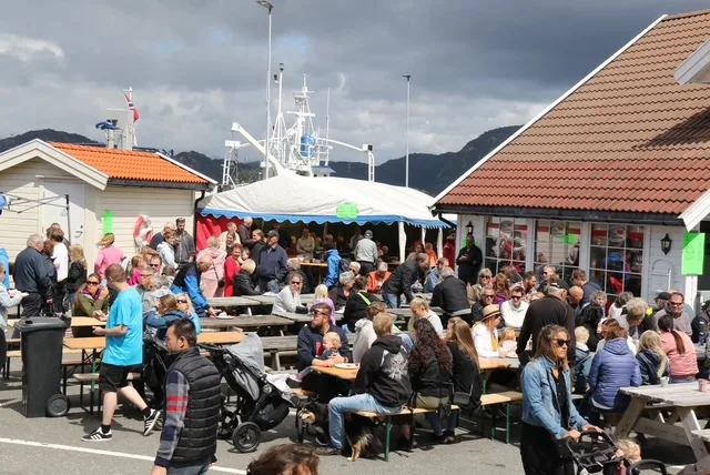Folk samlet ved langbord på kaia under Øynadagen