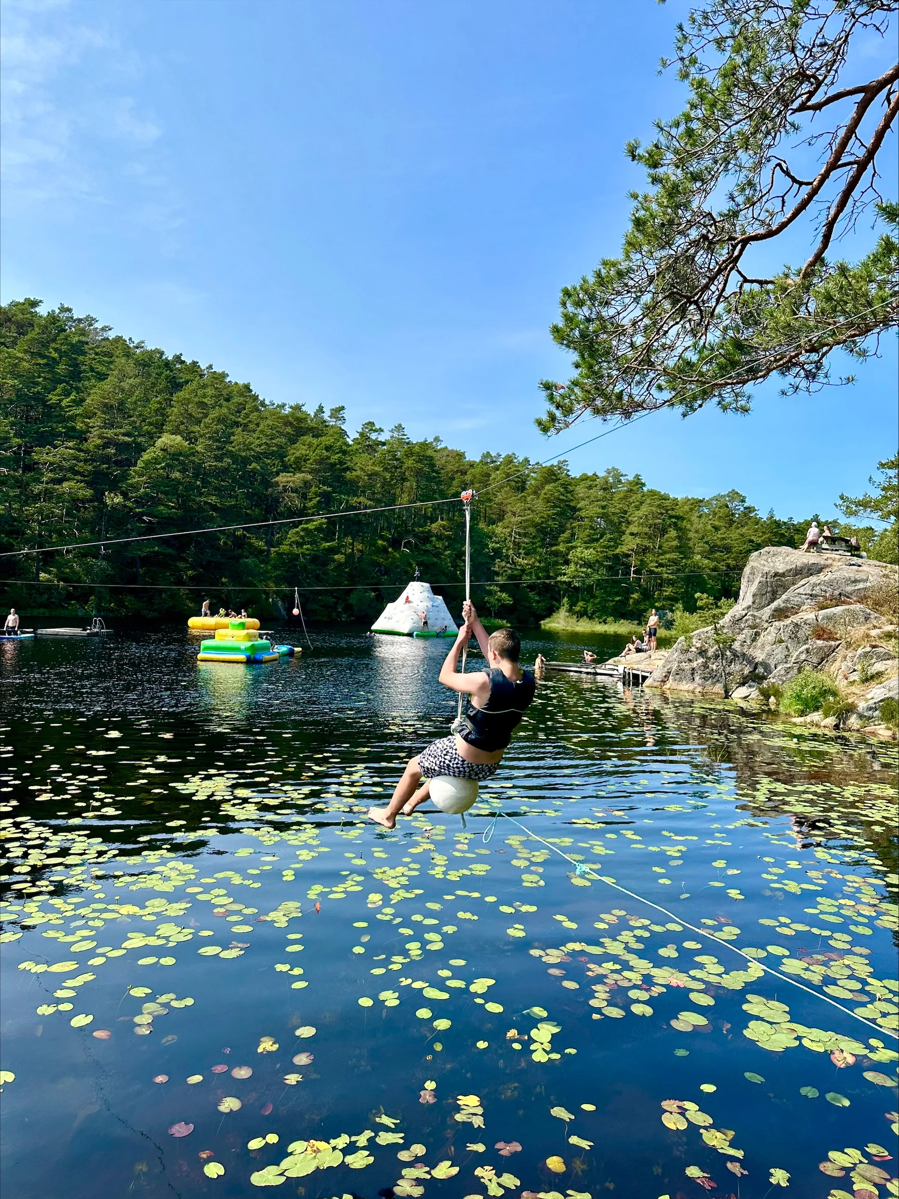 En person suser på zipline over Engelsvannet, med skog rundt