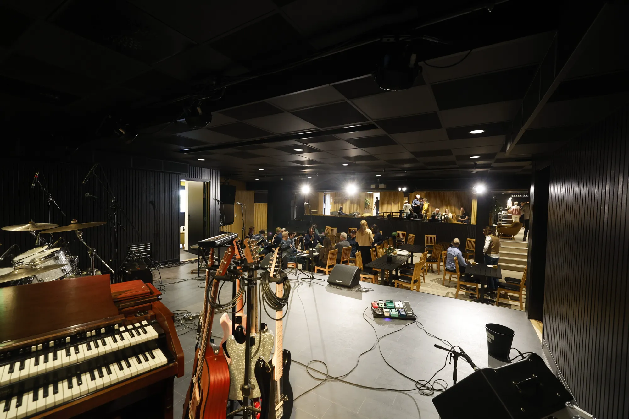 Utsikt fra scenen på Byremo Scene, med instrumenter i forgrunnen og publikumsbord bak