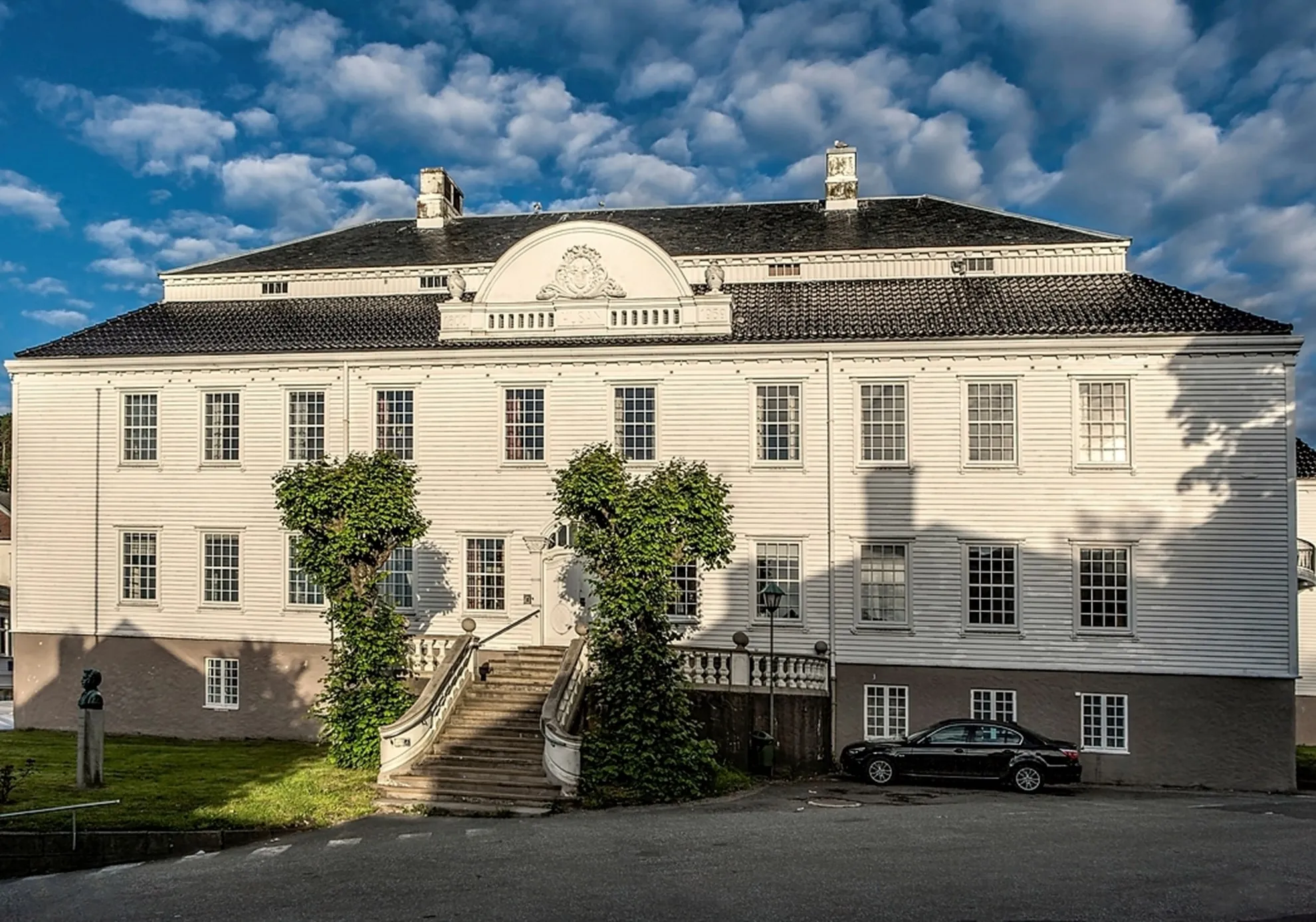 Husan, det hvite empirehuset som er rådhus i Farsund, med dobbel trapp og slyngplanter i kveldssol