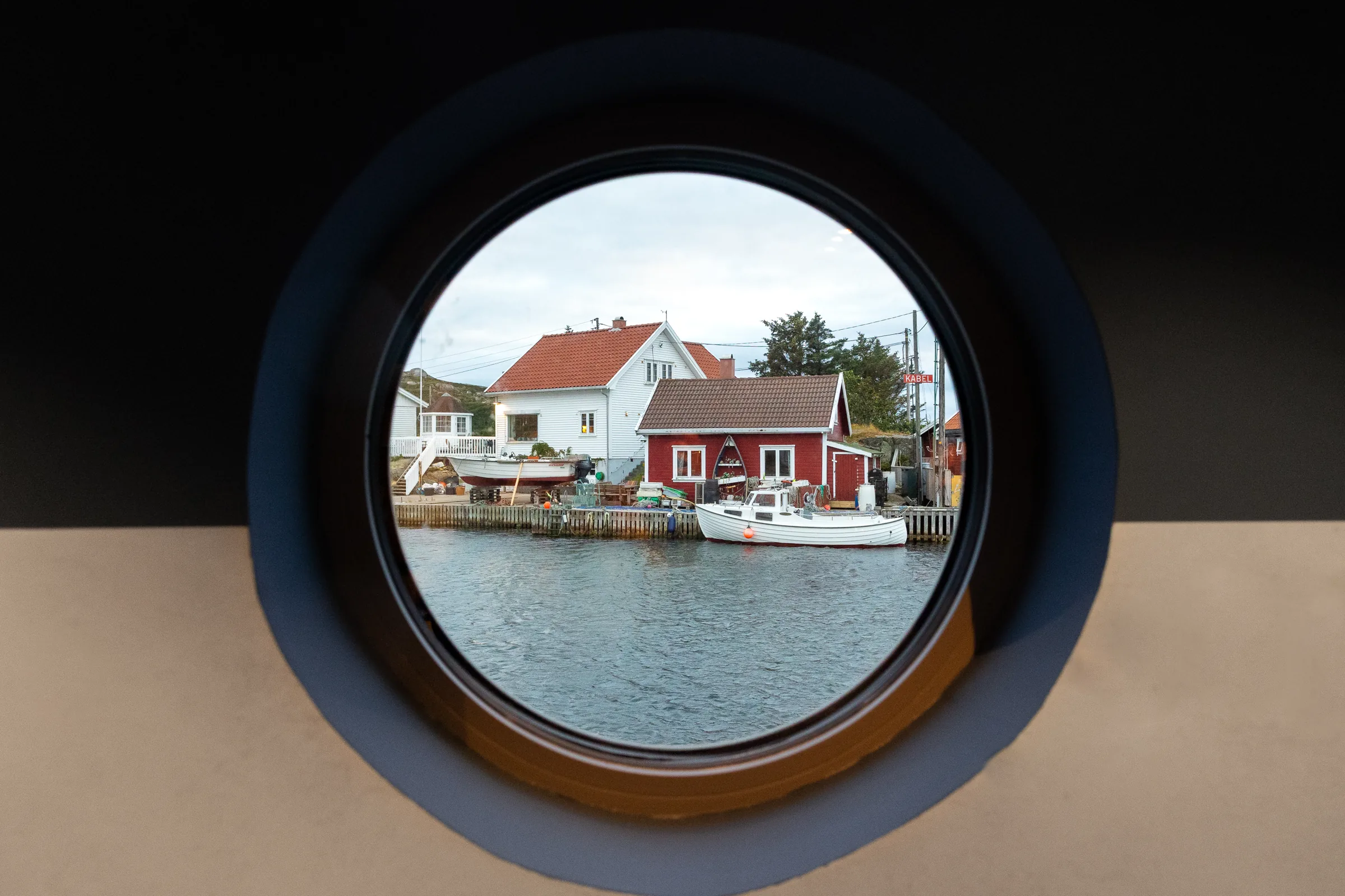 Havna i Korshamn sett gjennom et rundt koøye, med hvite og røde hus ved bryggene