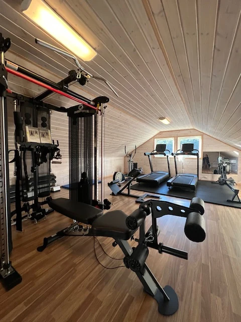 Styrkerom under skråtak med treningsapparater, tredemøller og vektbenk