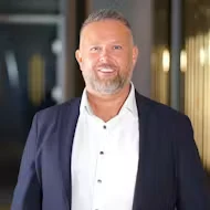 Portrett av Ronny Fredriksen i dress, smilende