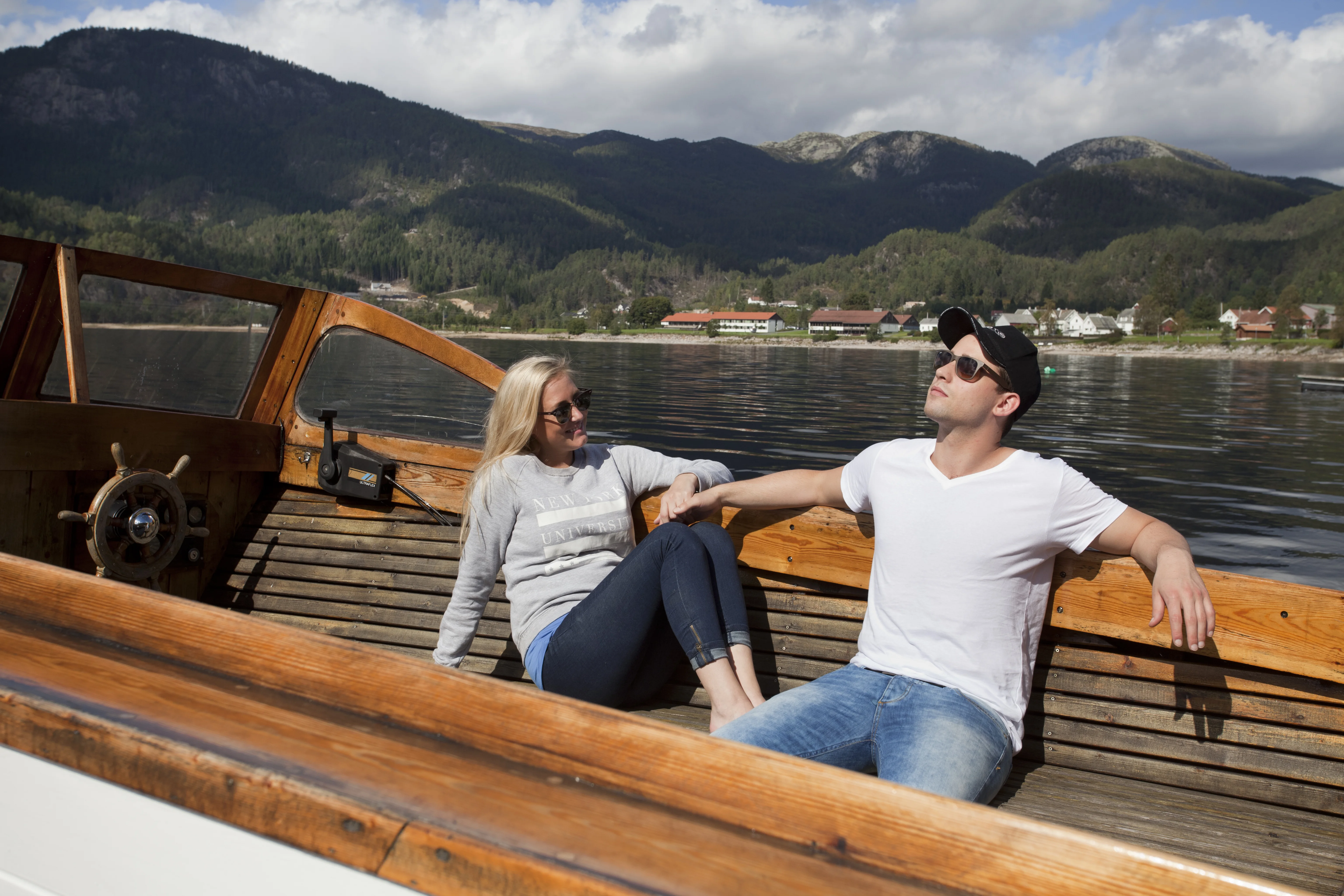 Et par slapper av i en gammel trebåt på Sirdalsvannet, med Tonstad og fjellene i bakgrunnen