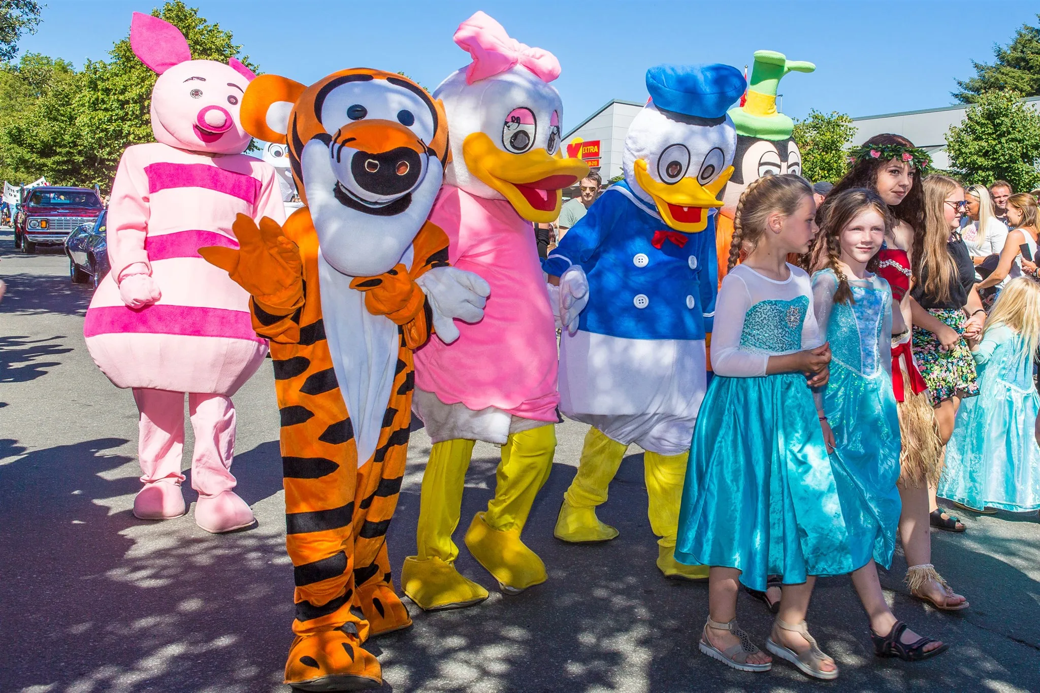 Barn i prinsessekjoler sammen med Nasse Nøff, Tigergutt og Donald Duck i gata under American Festival