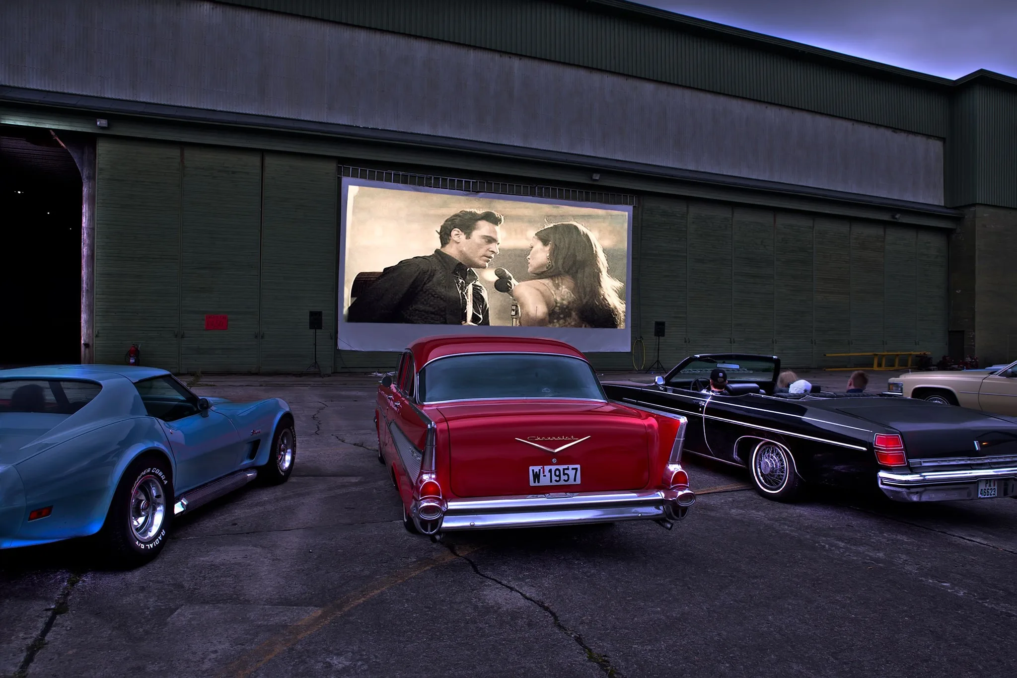 Utekino under American Festival: en rød Chevrolet og andre veteranbiler parkert foran et stort lerret med en filmscene i skumringen