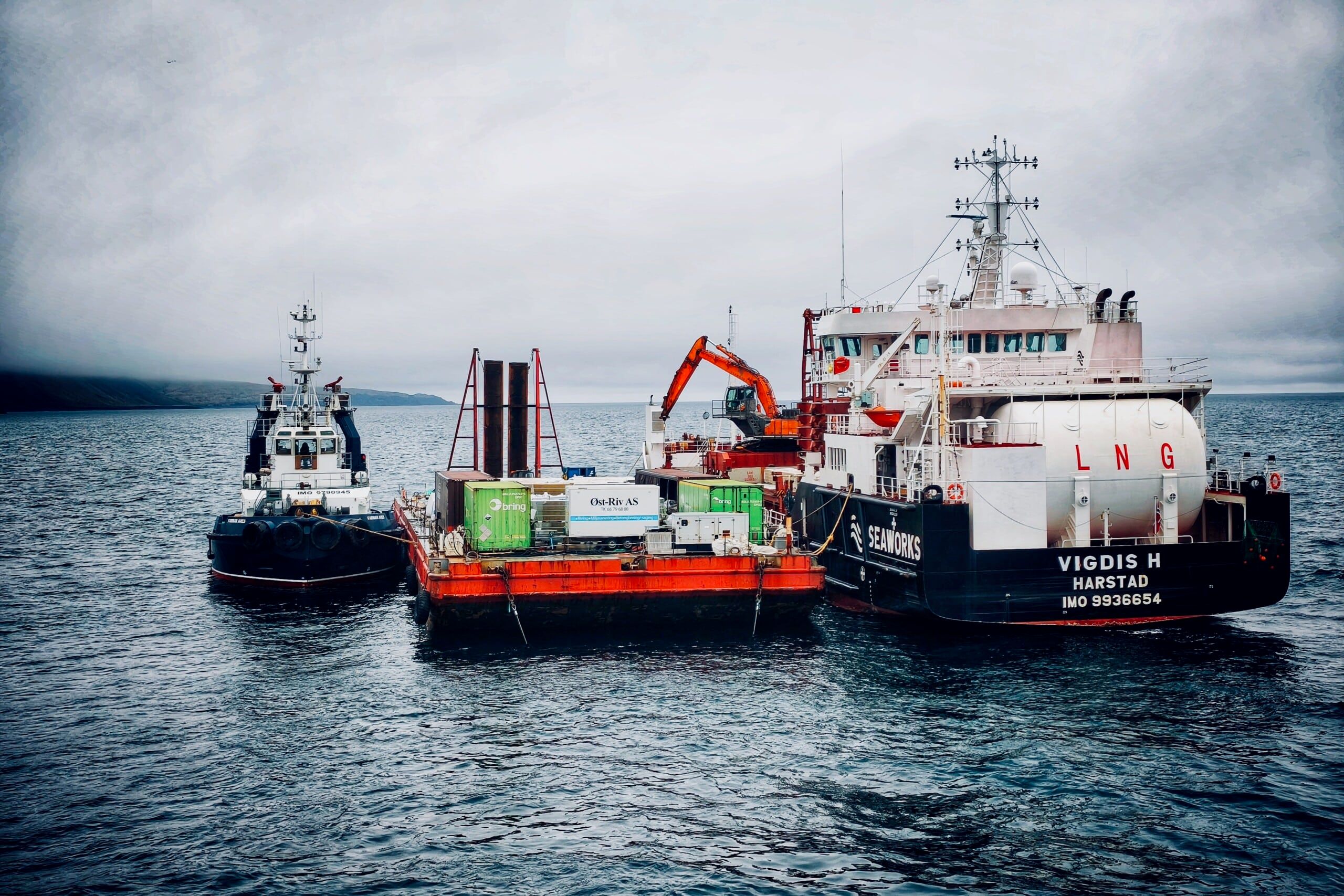 Farmars slepebåt og lekter med utstyr og gravemaskin i drift på havet