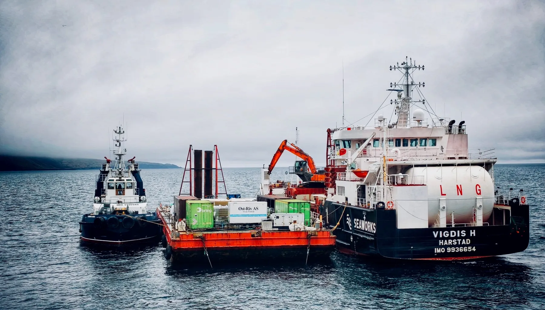 Farmars slepebåt og lekter med utstyr og gravemaskin i drift på havet