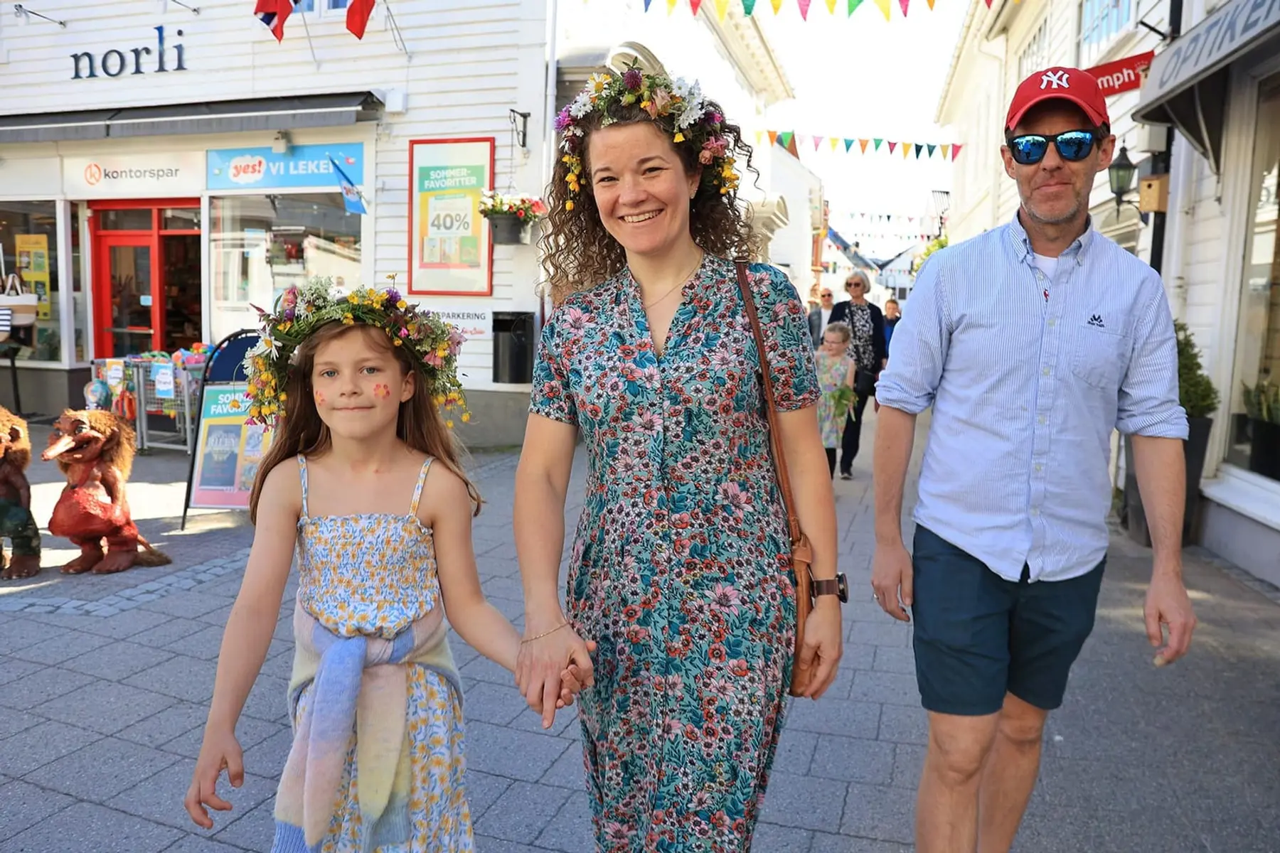 Familie på vei gjennom gata, jente med blomsterkrans