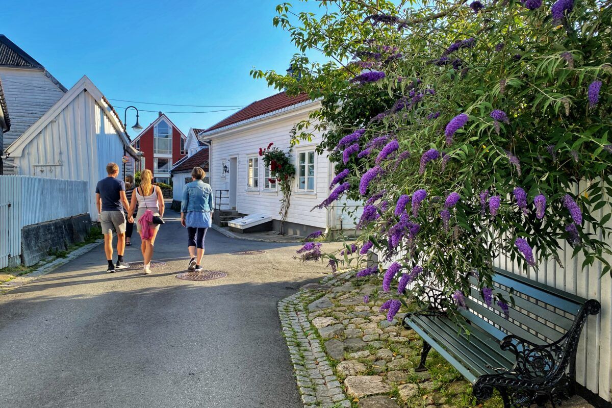 Folk på tur i en trehusgate i Flekkefjord om sommeren