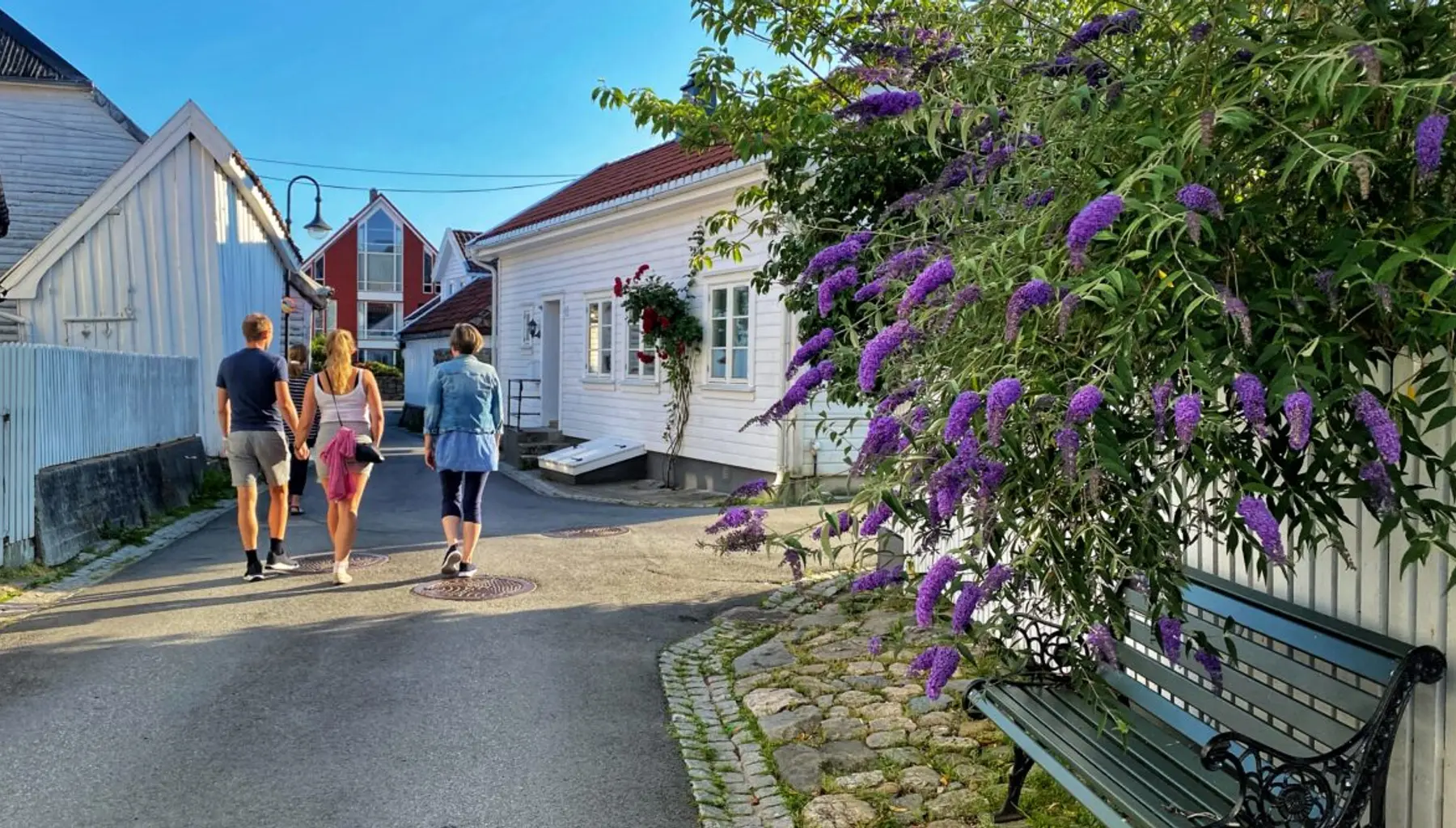 Folk på tur i en trehusgate i Flekkefjord om sommeren
