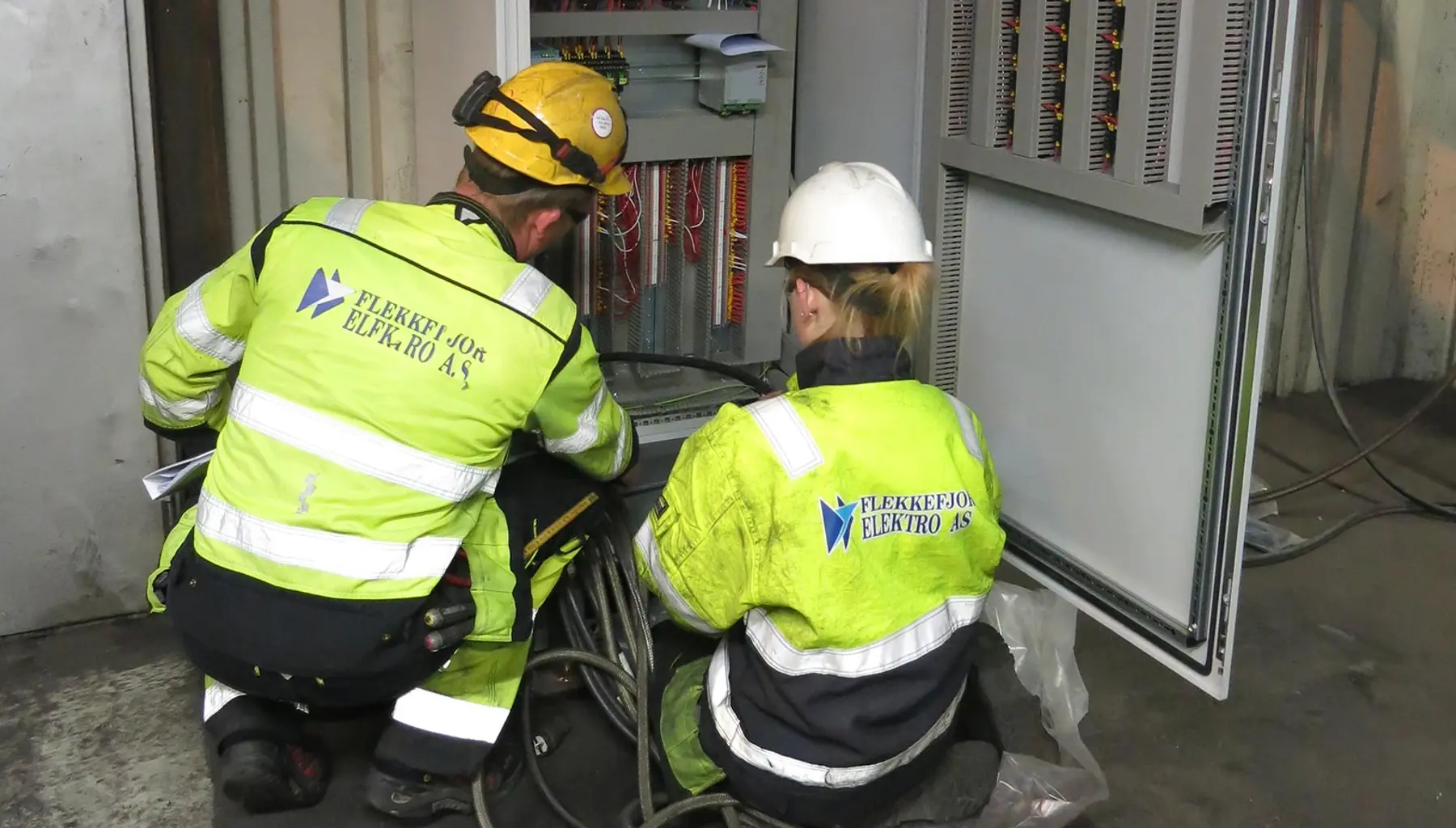 To montører fra Flekkefjord Elektro arbeider med et åpent styreskap