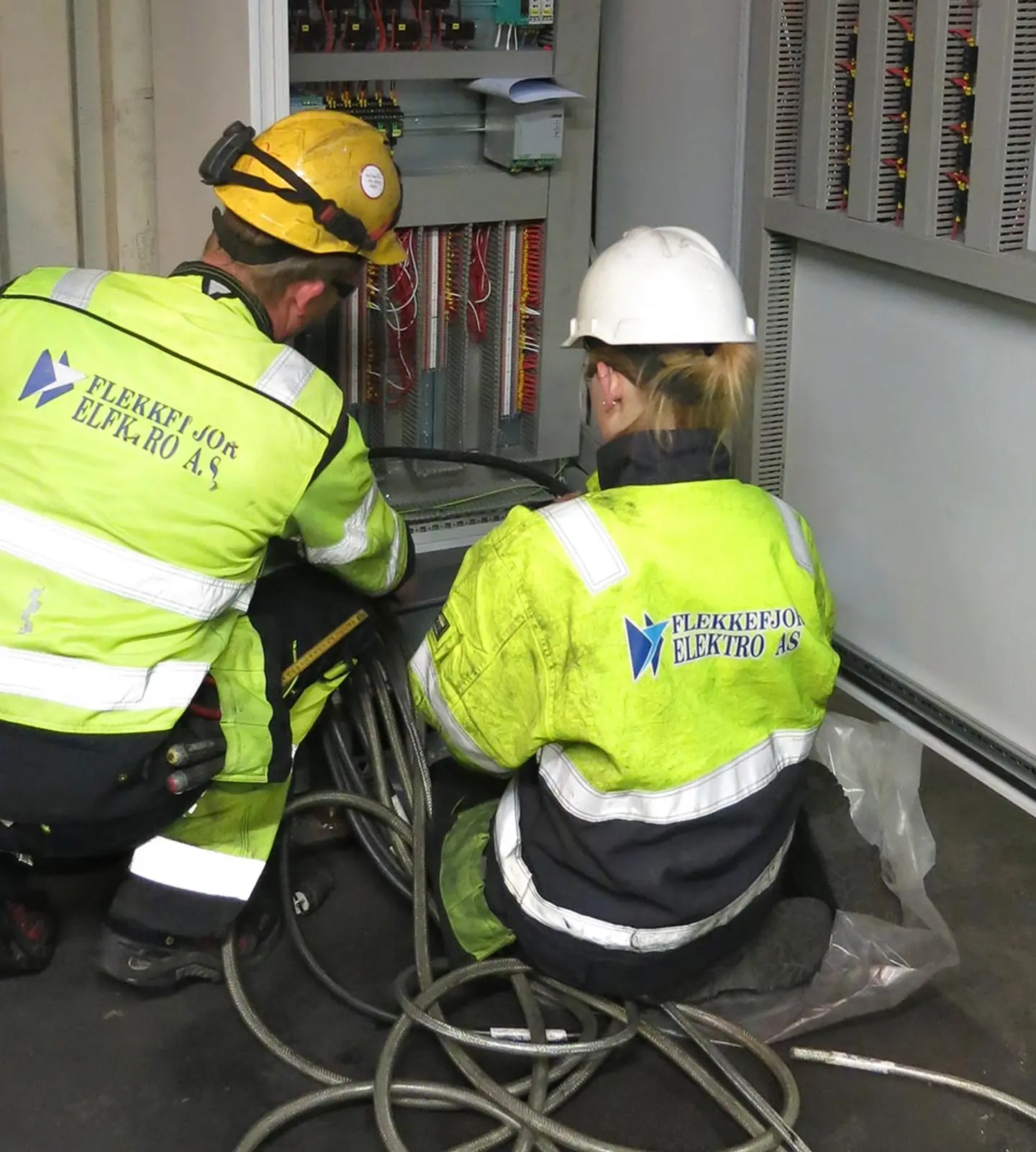 To montører fra Flekkefjord Elektro arbeider med et åpent styreskap