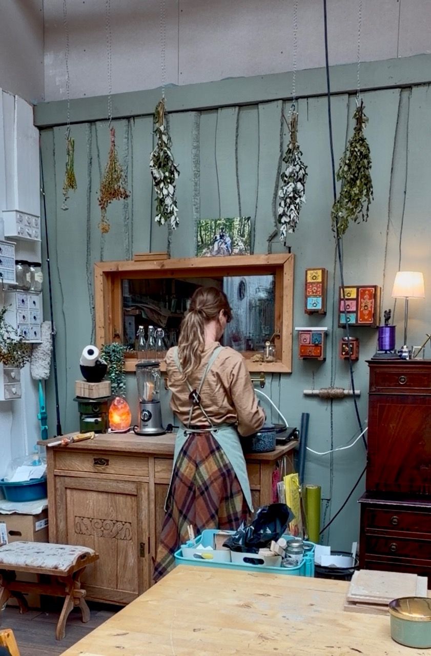 Jill arbeider i kunststudioet sitt, omgitt av tørkede urter som henger fra taket