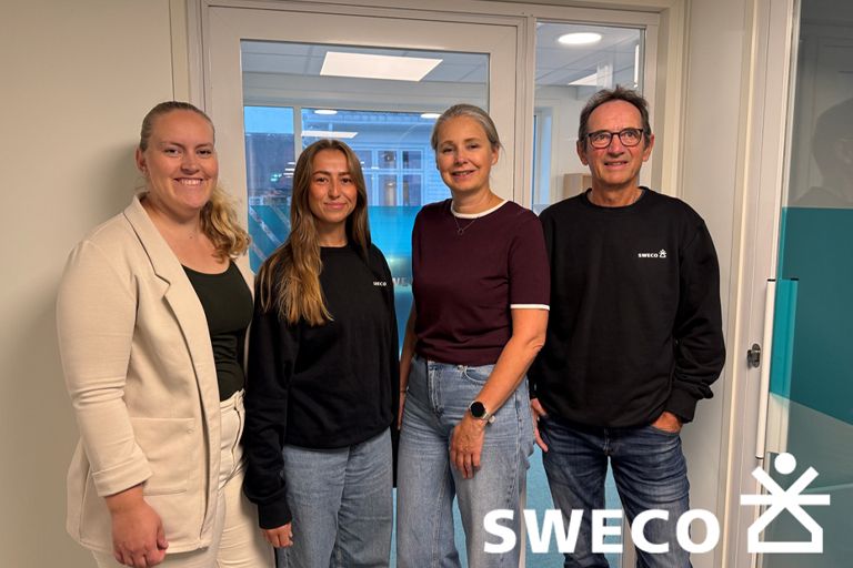 Fire ansatte i Sweco smiler foran et kontorlokale med Sweco-logo