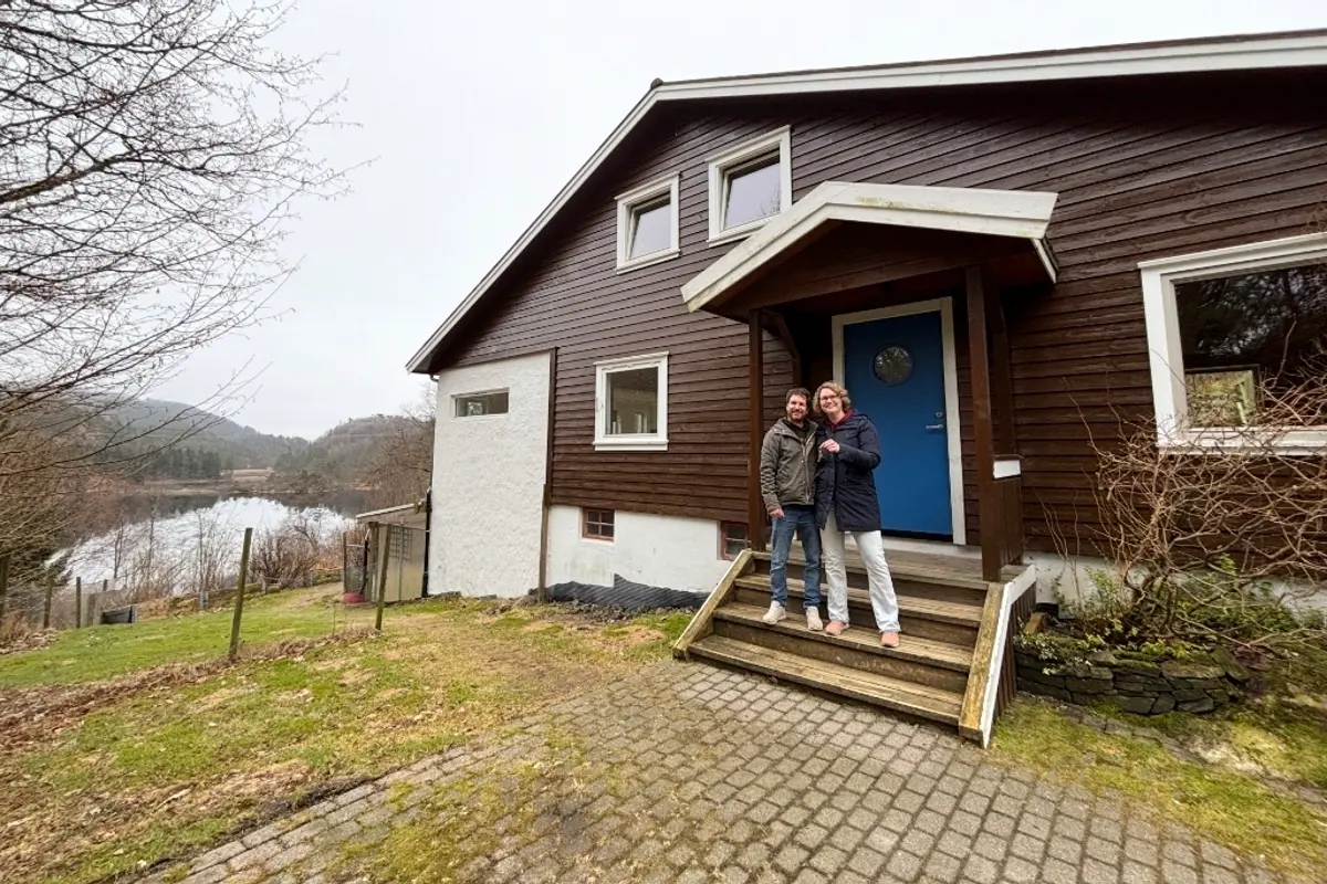 Jerry og Linda står på trappen foran huset sitt ved vannet i Feda.