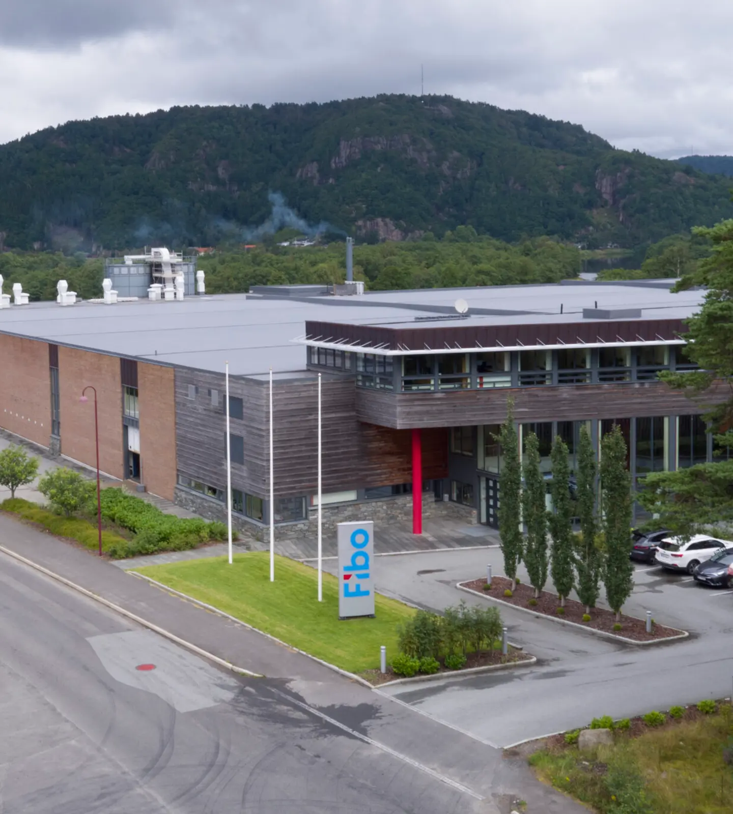 Fibos hovedkontor og produksjonsanlegg i Lyngdal sett ovenfra, med skiltet "Fibo" foran inngangen