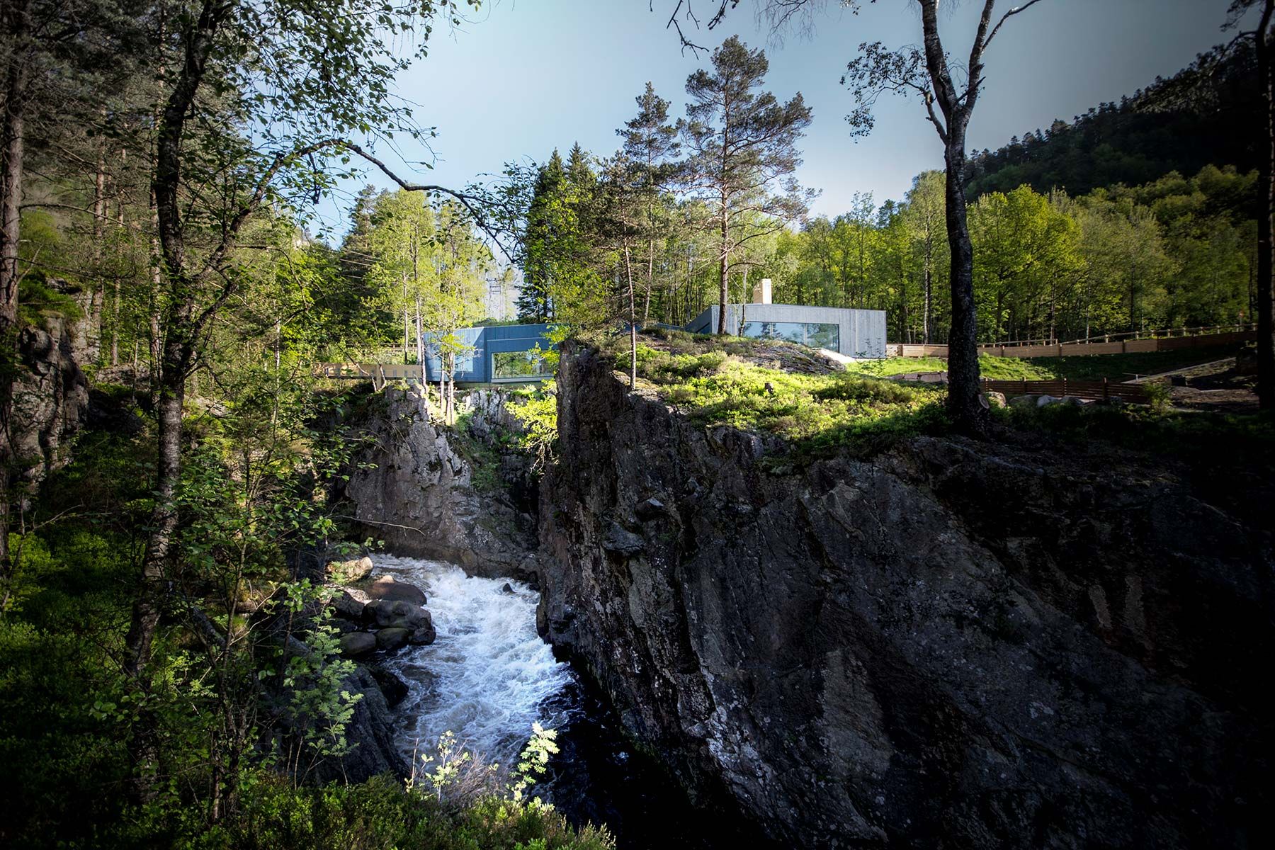 The wild salmon centre's building balances on the edge of the gorge above Kvåsfossen, surrounded by forest.
