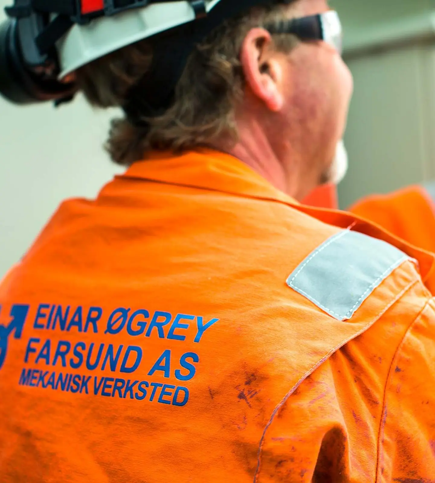 To ansatte i oransje arbeidstøy med Einar Øgrey Farsund-logo på ryggen, på et anlegg
