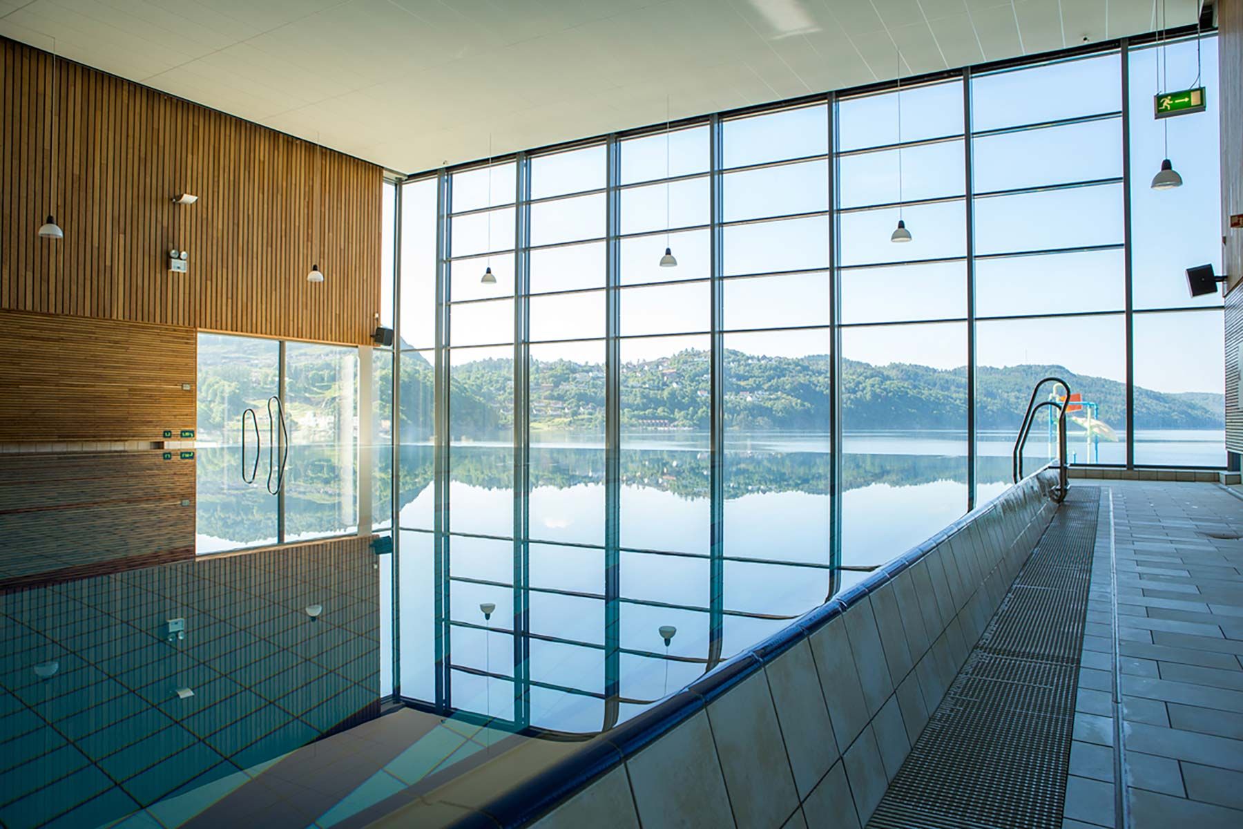 Innendørsbasseng hos Sørlandsbadet med store vinduer og utsikt mot fjorden
