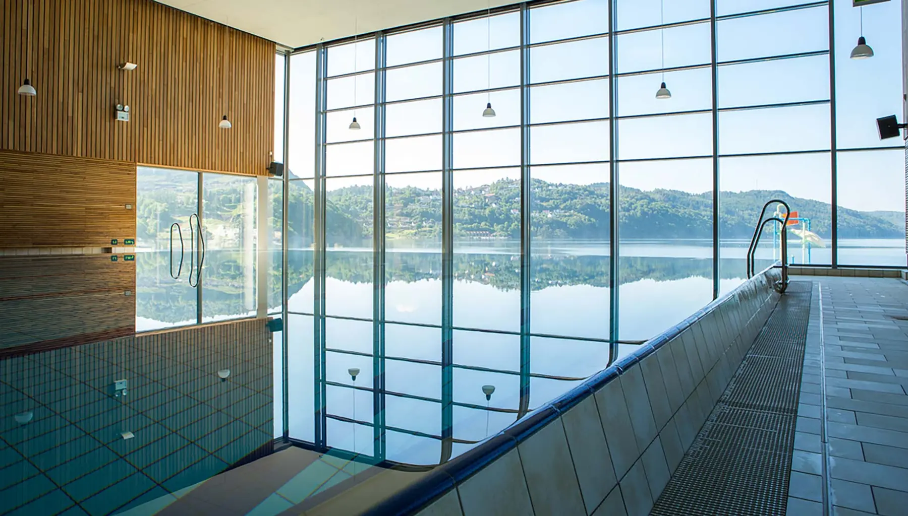 Bassenget hos Sørlandsbadet med utsikt mot fjorden gjennom store vindusflater