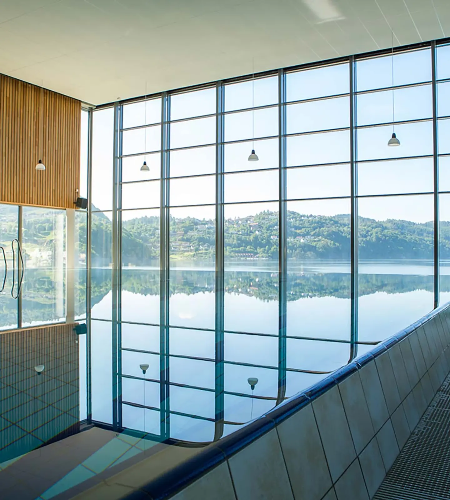 Innendørsbasseng hos Sørlandsbadet med store vinduer og utsikt mot fjorden