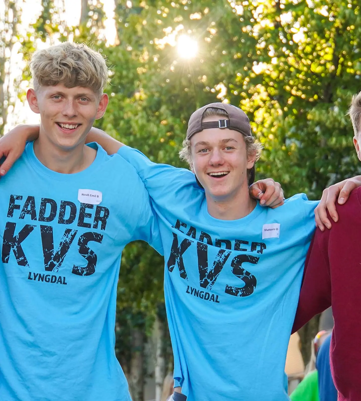 Fire glade gutter med armene rundt hverandre på KVS-Lyngdal, to av dem i blå «Fadder KVS»-t-skjorter