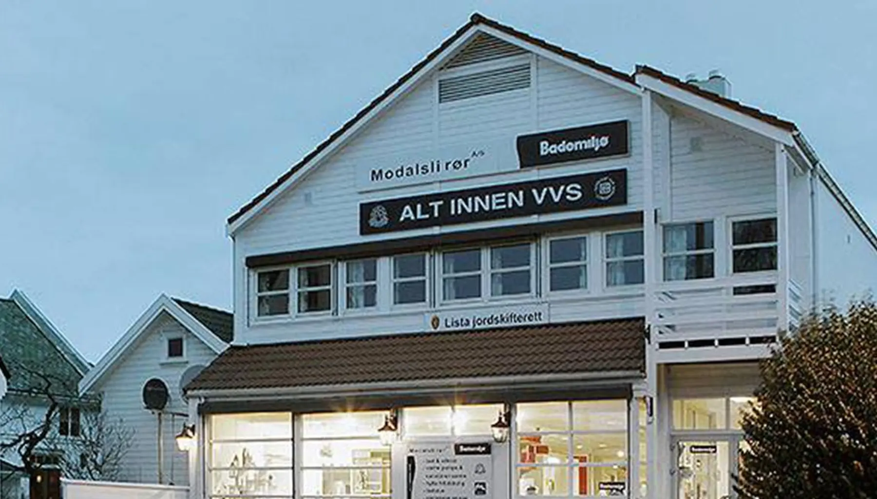 Bademiljø Modalsli Rørs hvite bygning i Flekkefjord sentrum i kveldslys, med skilt for «Alt innen VVS»