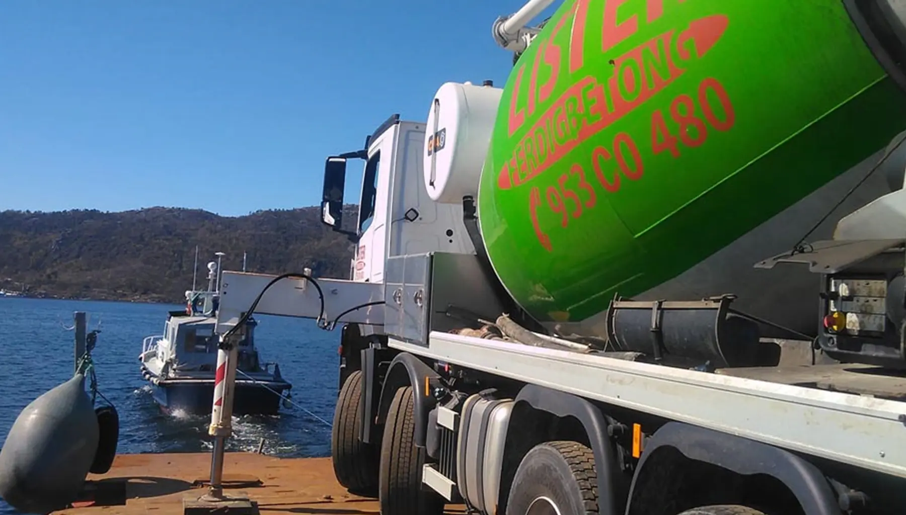 Betongbil fra Lister Ferdigbetong lastes fra kai, med fjorden og en mindre båt i bakgrunnen